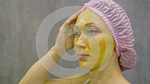 Procedure for skin care to face of young pretty woman. Beauty salon, facial peeling yellow gold alginate mask with