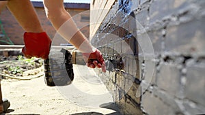 The process of applying black moisture protection to the fa ade of a house. A worker applies waterproofing to the fa ade