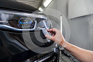 The process of applying a nano-ceramic coating on the car`s bumper by a male worker with a sponge and special chemical compositio