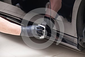 The process of applying a nano-ceramic coating on the car`s door by a male worker with a sponge and special chemical composition