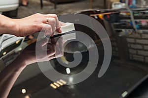 The process of applying a nano-ceramic coating on the car`s hood by a male worker with a sponge and special chemical composition photo