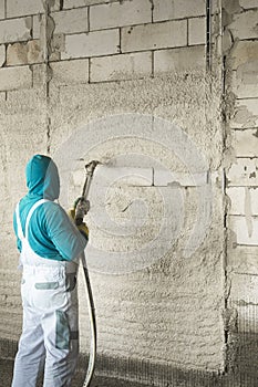The process of applying plaster to walls inside a building by machine.