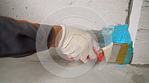 A worker is applying waterproofing paint to the floor in the bathroom. The process of applying waterproofing in the