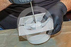 The process of assembling the kitchen exhaust fan after cleaning the wash. A man works with a screwdriver in his hands