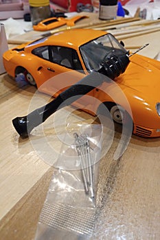 The process of assembling and painting the scale model of the car. Orange sports car in miniature. Manual mini drill