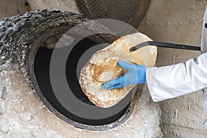 process of baking bread in a traditional Georgian stove - tone, tandoor. A male cook takes a fresh tortilla from the oven
