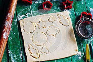 Process of baking cookies at home. Fresh dough ready for baking on rustic green wooden background. Dough ingredients and decoratio