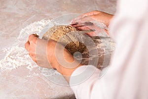 Process of baking health bread at home. closeup woman hands kneading dough from rye flour on marble countertop in bright kitchen