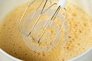 The process of beating eggs with sugar with a mixer, close-up, making the dough.