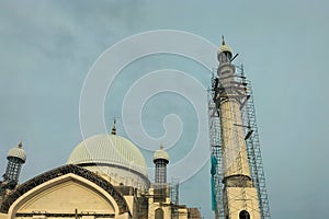 The process of building a new large mosque with several minarets. Exterior decoration works at height with the help of