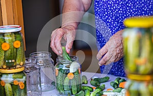 Process of canning a cucumber, senior woman canning fresh cucumbers with onion and carrots, homemade product, food