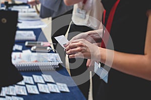 Process of checking in on a conference congress forum event, registration desk table, visitors and attendees receiving a name