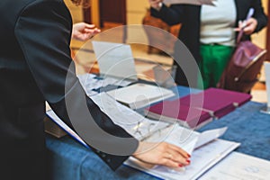 Process of checking in on a conference congress forum event, registration desk table, visitors and attendees receiving a name