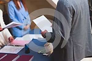 Process of checking in on a conference congress forum event, registration desk table, visitors and attendees receiving a name