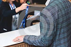 Process of checking in on a conference congress forum event, registration desk table, visitors and attendees receiving a name