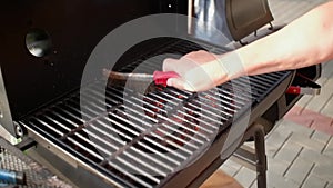 The process of cleaning the charcoal grill grates with a metal brush.
