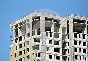 Process of construction high-rise modern apartment building with penthouses over blue sky in sunny day