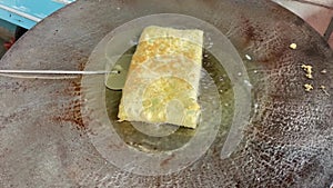 The process of cooking egg martabak or (Martabak telur) frying in hot oil in a wide frying pan