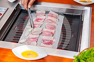 Process of cooking Korean barbecue raw pork on the tabletop grill in restaurant. Selective focus. close up. photo