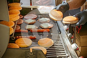 Process of cooking meat for burgers and cheeseburgers, sausages for hot dogs, buns on a grill with burning coals.