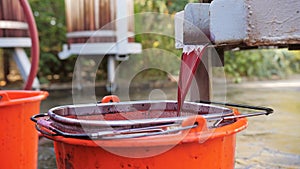 The process of creating craft wine in a private winery. The wine is poured from the fermentation barrel through a sieve