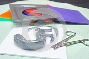 Process of creating custom mouthguard. Silver sports mouthguard with pieces of plastic material and tools