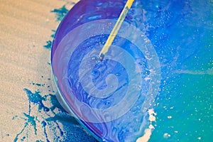 The process of creating a home-made trendy abstract modern pattern painted with a brush of acrylic blue multi-colored resin