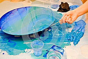 The process of creating a home-made trendy abstract modern pattern painted with a brush of acrylic blue multi-colored resin