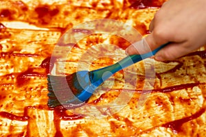 The process of creating a pizza. Pizza made at home. Smearing of ketchup on a batterless dough