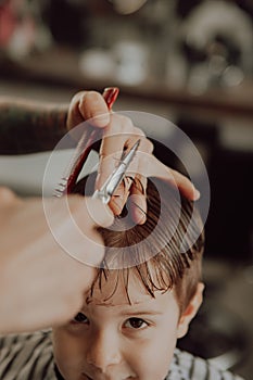 The process of cutting a boy`s hair in a barbershop