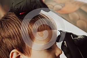 The process of cutting a boy`s hair in a barbershop