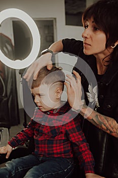 The process of cutting a boy`s hair in a barbershop