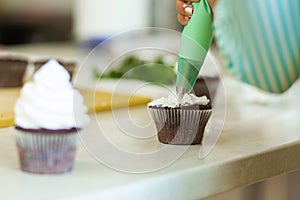 The process of decorating chocolate cupcakes with airy protein cream. Creation of cakes by professional pastry chefs