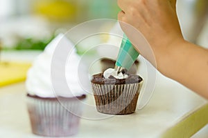 The process of decorating chocolate cupcakes with airy protein cream. Creation of cakes by professional pastry chefs