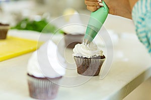 The process of decorating chocolate cupcakes with airy protein cream. Creation of cakes by professional pastry chefs