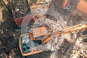 Process of demolition building dismantling aerial top view. Excavator breaking house