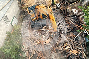 Process of demolition of old building dismantling. Excavator breaking house. Destruction of dilapidated housing for new