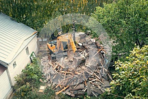 Process of demolition of old building dismantling. Excavator breaking house. Destruction of dilapidated housing for new