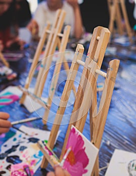 Process of drawing, group class of talented students with painting easels and canvases during lesson of watercolour painting