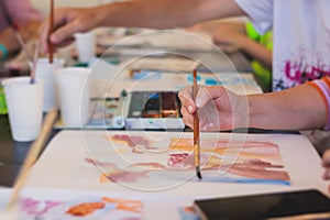 Process of drawing, group class of talented students with painting easels and canvases during lesson of watercolour painting