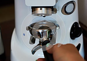 The process of grinding grain into holder for making espresso on coffee machine. Barista job at the coffee shop.