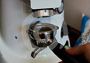 The process of grinding grain into holder for making espresso on coffee machine. Barista job at the coffee shop.