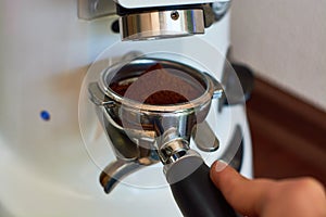 The process of grinding grain into holder for making espresso on coffee machine. Barista job at the coffee shop.