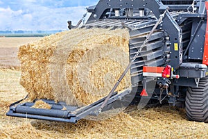 The process of harvesting grain in an agricultural field, forming sheaves of straw into tight briquettes