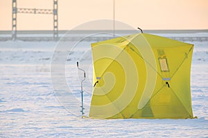 Process of ice fishing, group of fishermen on ice near tent shelter, with equipment in a winter snowy day, tents and ice auger on