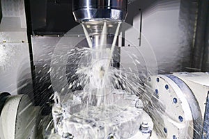 A process of industrial wet milling in 5-axis cnc machine with coolant flow under pressure and motion blur of splashes