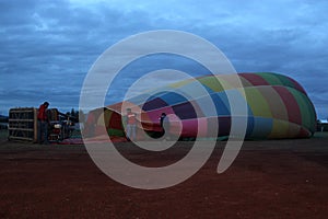 process of inflation and preparation of hot air balloon at sunrise for flight in cloudy sky