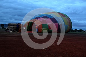 Process of inflation and preparation of hot air balloon at sunrise for flight in cloudy sky