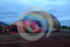 Process of inflation and preparation of hot air balloon at sunrise for flight in cloudy sky