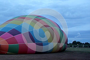 Process of inflation and preparation of hot air balloon at sunrise for flight in cloudy sky